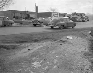 Another dismal scene with old cars and muddy sides of the road.