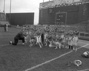 Arnie kneels by the boys on the field.