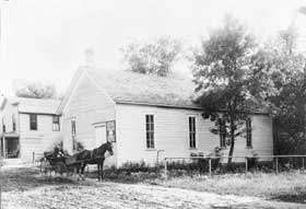 Wooden structure with horse and buggy in front.